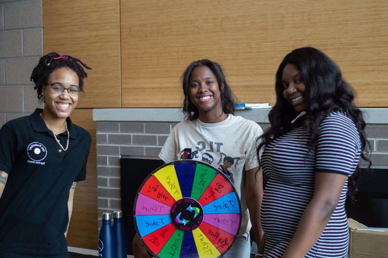 students smiling for photo with spinning wheel