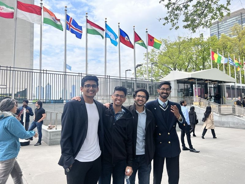 four students smiling in front of flags